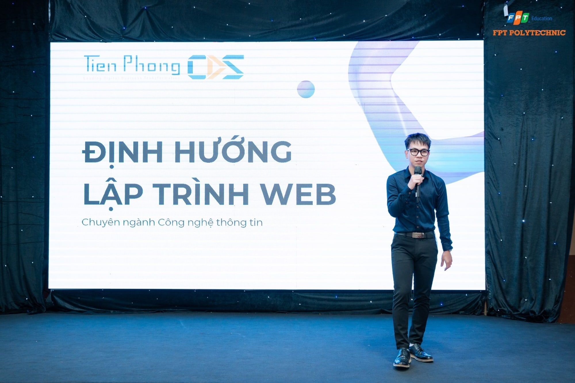 Phát biểu trên sân khấu, phía sau là slide Định hướng lập trình web